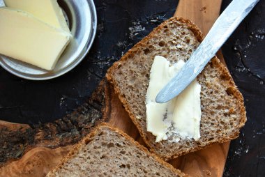 Tereyağlı bir parça ekmek. Kahvaltı için tereyağı ve ekmek kırsal ahşap arka planda. Üst görünüm.