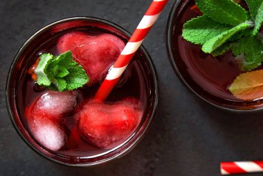 Koyu arkaplanda kalp şeklinde buz küpleri olan dut kokteyli..