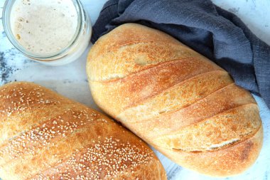 Ev yapımı beyaz ekmek, bir somun ekşi ekmek. Taze ekmek ve mayalı mayalı cam bir kavanoz..