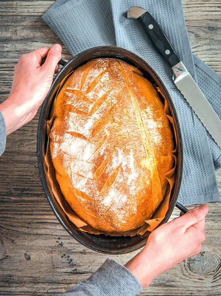 Hands holding a pan of freshly baked bread, top view