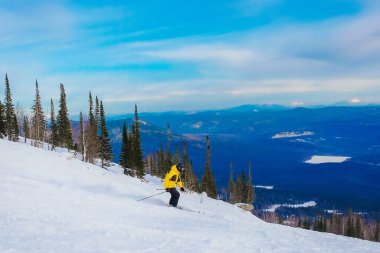 Kayak merkezi. Serbest bırak. Sheregesh dağlarında snowboard yapan genç bir adam. Mavi gökyüzünün arka planında beyaz bir snowboardcu. Beyaz kar kayakçısının stili.