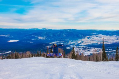 Kayak merkezi. Serbest bırak. Sheregesh dağlarında snowboard yapan genç bir adam. Mavi gökyüzünün arka planında beyaz bir snowboardcu. Beyaz kar kayakçısının stili.