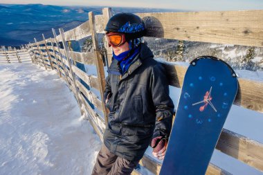 Sheregesh dağlarında başarılı bir snowboard sporcusu. Snowboardcu dağın tepesinde dinleniyor. Mavi gökyüzünün arka planında beyaz bir snowboardcu. Beyaz kaykaycı, şık biri. kayak merkezi