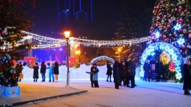Novosibirsk, Rusya, 31.12.2020: Noel ağacı yakınlarındaki halk festivalleri ve kırmızı yıldız, balon ve çelenk şeklinde yeni yıl süslemeleri
