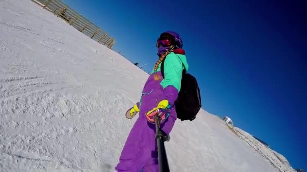 Sheregesh, Russia, 02.21.2020: Woman snowboarder rides a snowboard down a mountain and shoots selfie on camera — Stock Video