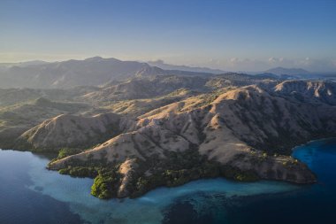 Komodo 'daki Rinca Adası engebeli tepeler ve turkuaz kıyıları gösteriyor. Kuru toprak ve mangrovların karışımı macera dolu çarpıcı bir manzara yaratır..