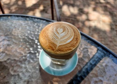 Masanın üzerinde bir fincan sıcak latte sanat kahvesi ve bulanık arka plan perspektifi..