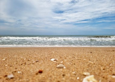 Bulanık sahil kumundan mavi gökyüzü arka planındaki denize bakış açısı.