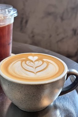 Bir fincan sıcak latte sanatının dikey çekimi masanın üzerindeki basit lale kahvesi..