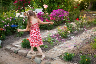 Mutlu kız çiçek açan bir yeşil bahçe çalıştıran