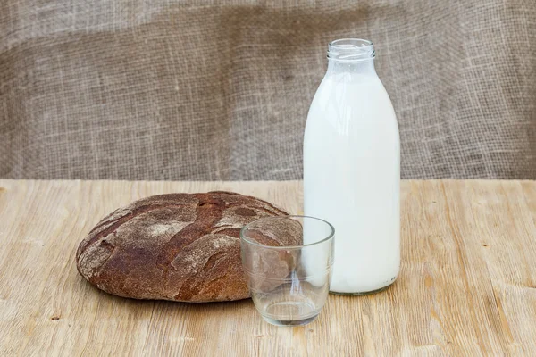 Pan de centeno con botella de leche sobre mesa de madera —  Fotos de Stock