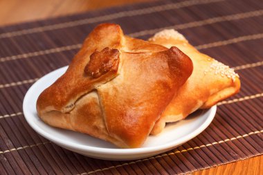 Pasties stuffed meat on bamboo napkin, close up clipart