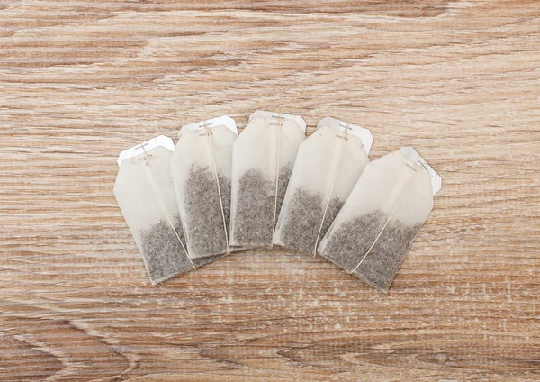 Sacchetti di tè inutilizzati in fila su sfondo di legno — Foto Stock