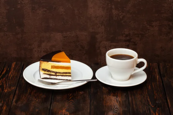 Orangenkuchenscheibe und Kaffeetasse auf Holzgrund — Stockfoto