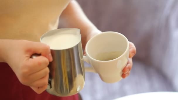Pouring stream milk, barista prepares latte in cup
