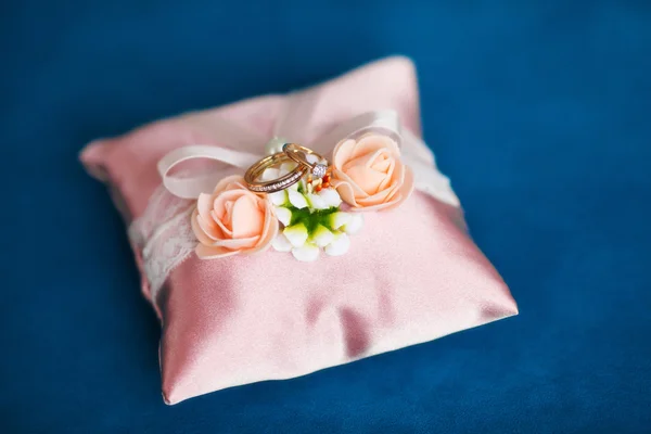 Anelli nuziali dorati su un cuscino rosa decorato. Concetto di matrimonio — Foto Stock