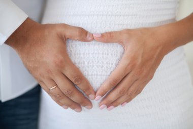 Koca bir kalp şeklinde hamile karnına eller