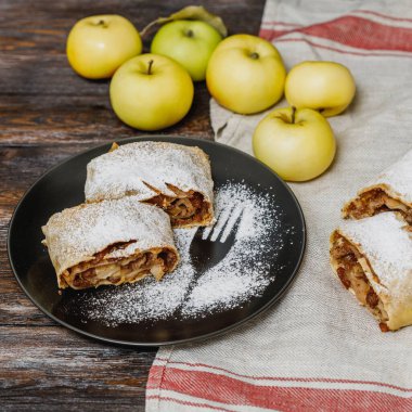 Elmalı turta, kremalı şeker ve siyah tabakta kuru üzüm, ahşap arka plan. Kare resim