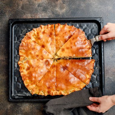 Büyük pişmiş balık turtası. Patates ve soslu. Tepsinin üstünde.