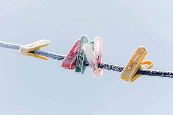 Colorful clothespins on clothesline covered with snow outdoors. Winter scene, housework concept