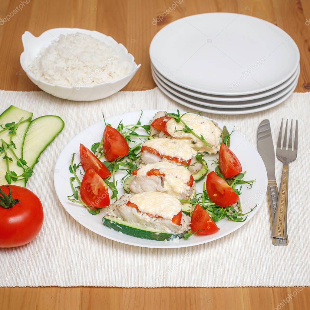 Baked fillet of codfish served with zucchini and tomatoes. Healthy organic food