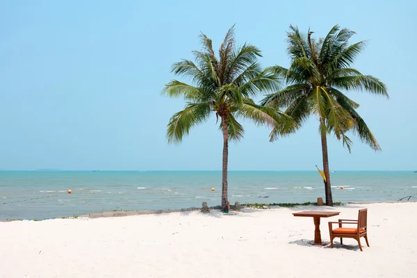 Krzesło i stół ustawiony na czystej piaszczystej plaży z palmami kokosowymi i piękne morze. — Zdjęcie stockowe
