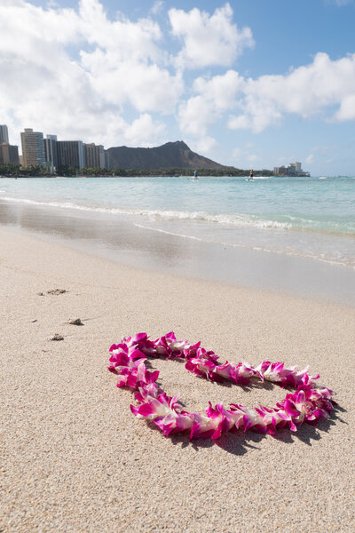 orchid flower garland necklace in love heart shape on white sea sand beach, romantic couple honeymoon trip at Hawaii .