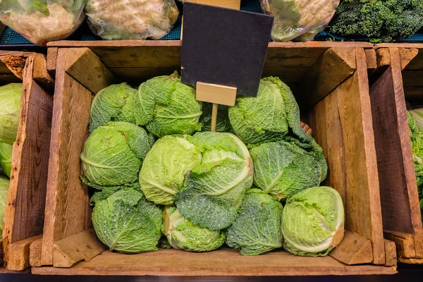 Färsk kål grönsaker i trä låda spilta i byn med blank griffeltavla etikett. — Stockfoto