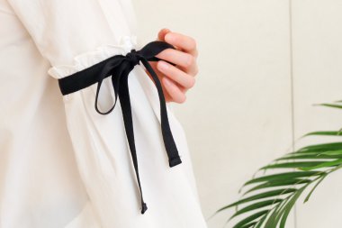 Uzun beyaz kol siyah string papyon stil detayları ile üzerinde el kadın. Trendy moda kadar kapatın.