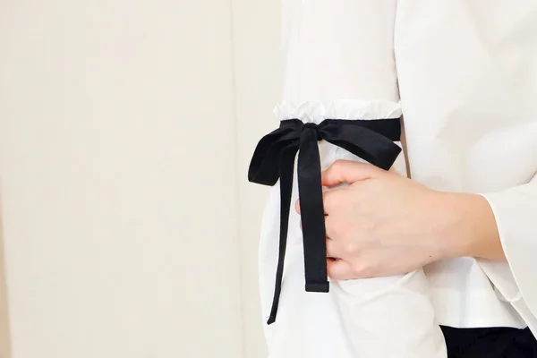 Woman hand on long white sleeve with black string bow tie style details. Close up trendy fashion.