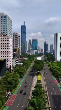 Jakarta, Endonezya, 13 Aralık 2025: Havadan insansız hava aracı görüntüleri, hareket halindeki arabalar ve şehir trafiği ile Jenderal Sudirman Caddesi, Jakarta 'da yoğun bir şehir caddesini gösteriyor.
