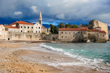 Karadağ 'ın Budva limanı, tarihi Eski Şehir' e ve Aziz John Katolik Katedrali 'nin çan kulesine bakıyor. Fotoğrafta limandaki tekneler, kıyı mimarisi ve Akdeniz atmosferi görülüyor. Uygun.