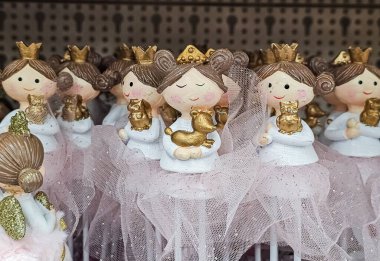 Süslü prenses heykelcikleri. Taçlar takıyorlar ve açık renkli elbiseler giyiyorlar. Yarı şeffaf etekleri var..