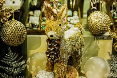 Altın Noel baloları ve dekoratif geyikler bir mağaza vitrininde sergileniyor. Bir perakende mağazasında sezonluk tatil dekorasyonu fotoğraflandı.