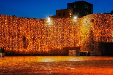 Karadağ 'ın Budva kentindeki parlayan Noel çelenkleriyle süslenmiş bir duvarın yatay fotoğrafı. Mevsimlik pazarlama, tatil illüstrasyonları ve şenlikli geçmişler için uygundur..