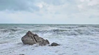 Güçlü okyanus dalgaları büyük bir kıyı kayasına çarpıyor. Doğal deniz hareketi ve su dramatik bir deniz sahnesinde sıçrar..