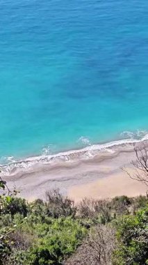 Turkuaz deniz manzaralı, kayalık plajlı ve kıyı boyunca dağılmış taşlar. Manzaralı kıyı görüntüsü