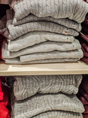 Gri kazaklar düzgünce bir rafa dizilmiş.