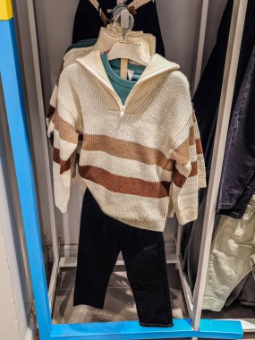 Askıda çocuk süveteri ve siyah pantolon asılı..