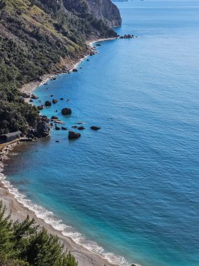 Turkuaz deniz ve kumlu sahil manzarası ve dağ manzarasıyla karşılaşan dağların tepeden görünüşü yaz tatili ve doğa içeriği için mükemmel.