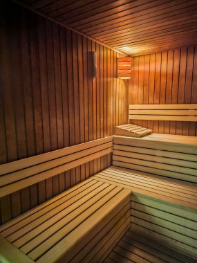 Ahşap duvarın detaylı görüntüsü ve saunanın içindeki bank. Saunada rahat ve sıcak atmosfer. Sağlık ve spa içeriği için ideal.