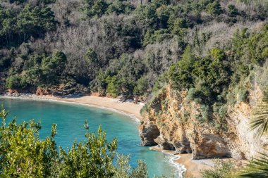 Kumlu bir sahil, kayalık kayalıklar ve mavi denizli tepeden aşağı bir kıyı manzarası. Seyahat, doğa, yaz, manzara ve açık hava yaşam tarzı içeriği için mükemmel..