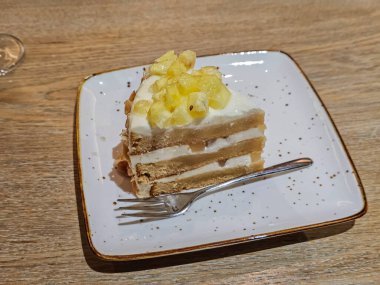 Tabakta servis edilen bir dilim ananaslı kekin yan görüntüsü. Yemek fotoğrafçılığına, yaşam tarzına ve fırın içeriğine uygun tatlı ve mutfak konsepti.