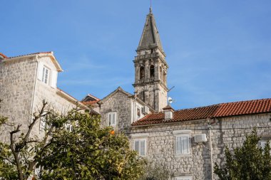 Karadağ 'ın Perast kentindeki tarihi Katolik kilise çan kulesinin açık mavi gökyüzüne karşı yatay görüntüsü. İkonik mimari ve kültür mirası, seyahat, turizm ve Avrupa tarihi kent içeriği için ideal.