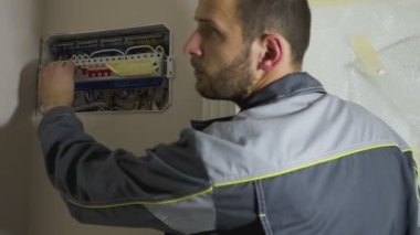 Yakışıklı genç elektrikçi evdeki santralde çalışıyor.