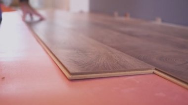 Çalışan adam eve lamine döşeme döşeme döşeme ve lamine kalasları birbirine bağlıyor..