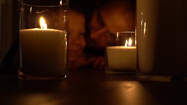 Pai beijando filho perto velas acesas no escuro. Família feliz comemorando aniversário de crianças — Vídeo de Stock