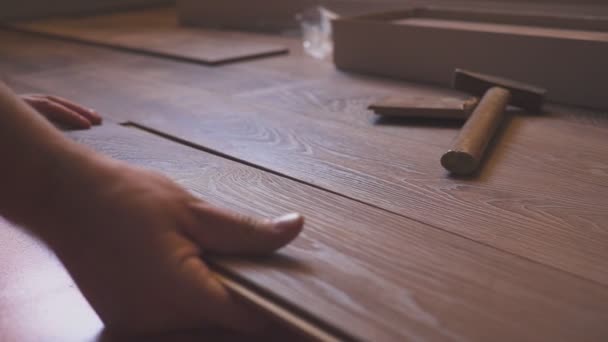 Working man installing laminate flooring in the house and connecting the laminate planks together. — Stock Video