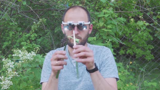 Selección de planta joven. Investigación de plantas usando una lente. Agricultor en gafas especiales examina las raíces de las plantas jóvenes. — Vídeo de stock