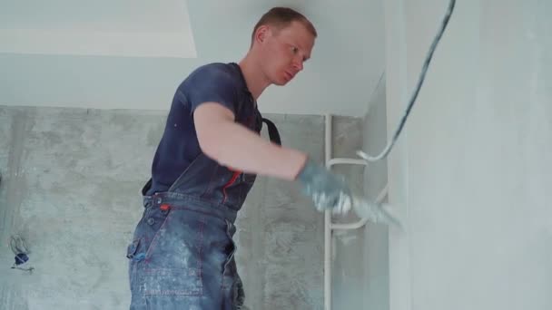 Operaio uomo sta facendo la riparazione in appartamento mettendo stucco sulle pareti. Casa di costruzione. — Video Stock